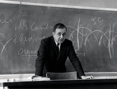 Black and white photo of Ed Callahan in front of a chalkboard