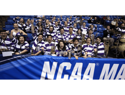 Band members cheering behind an NCAA sign