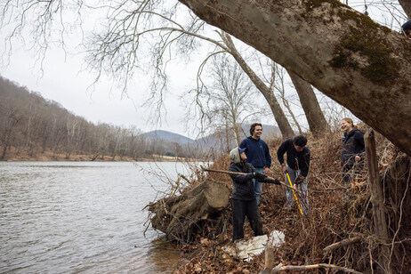 Students with shovels and sticks on the banks of a river