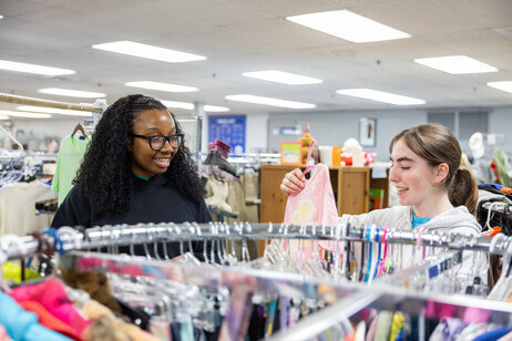 Two students hanging clothes on a rack