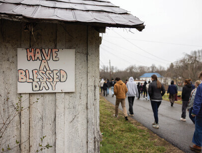 Students walking past a building with a sign that reads "Have a blessed day"