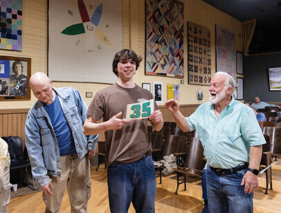 Three men, with the one in the center holding a sign with the number 35