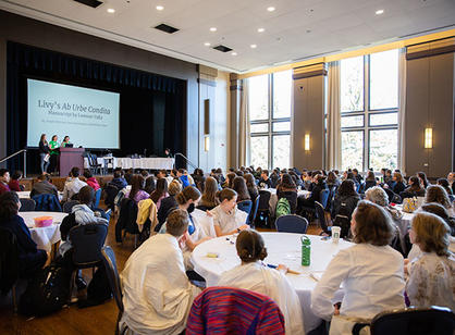 Students walk on the Fenwick Porch, which is lit purple for the occasion.