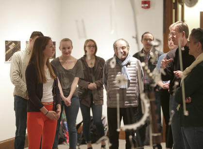 Rev. Philip L. Boroughs, S.J., president of the College, asks senior studio art major Mary Welsh '17 about her sculpture "Eruption" during the Academic Conference.