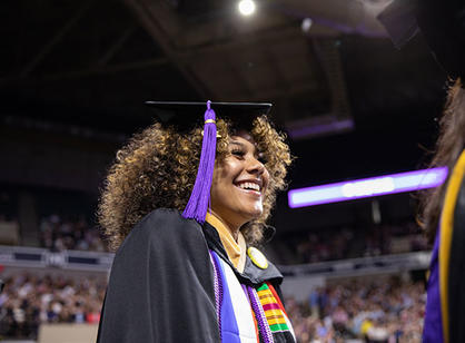 A student excitedly stands in line to receive their diploma.