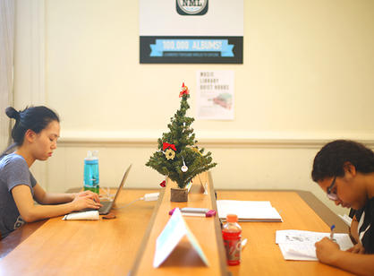 Students study for finals next to a tiny Christmas tree in the Music Library.
