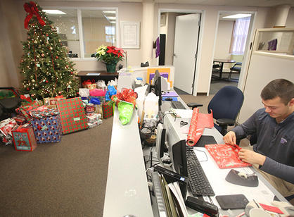 Presents collected for the annual Giving Tree drive surround an adorned tree in Human Resources.