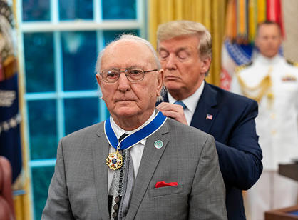 The president puts a medal around Bob Cousy's neck