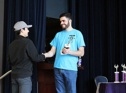 A Holy Cross classics major hands an award to a high school student competing in Certamen.