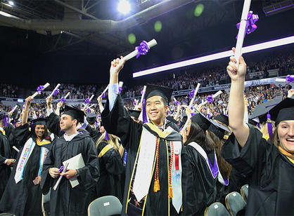 A student waves while holding their diploma.