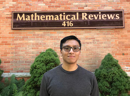 A student stands in front of the sign for the American Mathematical Society