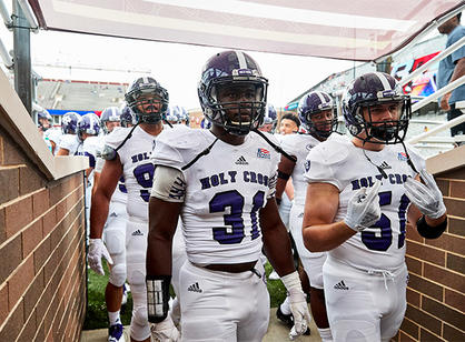 holy cross football players walk onto field