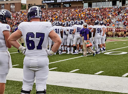 football team huddles on field