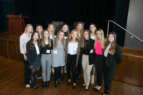 Group of female students gathered in front of a stage.