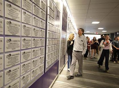 Attendees explore the Varsity Club Hall of Fame plaques lining a hallway of the athletic complex during the dedication celebrations.