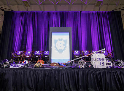 Set up in the basketball arena for the speaking program, the stage is decorated with equipment representing each of the College's 27 varsity athletic teams.