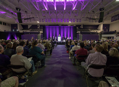 The basketball arena is full of members of the Holy Cross community, who have gathered to celebrate the dedication of the new athletic complex.