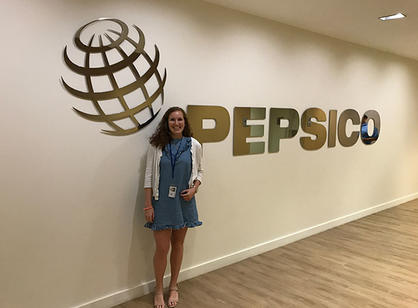 A student stands next to a PepsiCo sign