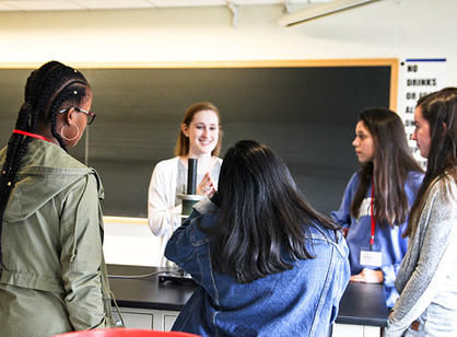 Students gather around a microscope