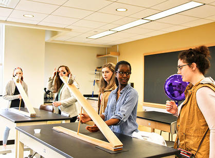 Students stand around a table with large pieces of wood