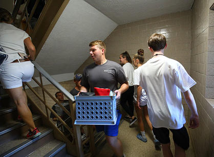 a student carries a box up stairs
