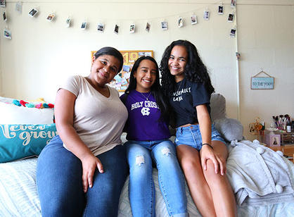 three students sit on a bed