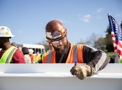 A construction worker signs the beam