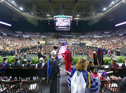 A student walks across the stage to receive their diploma from Rev. Philip L. Boroughs, S.J.