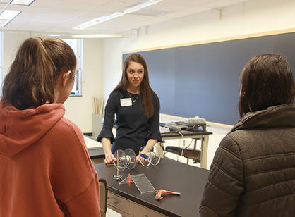 Abby Corrigan '19 talks to high school students in a laboratory.