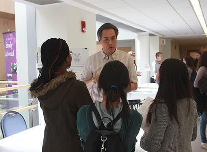 A professor speaks with high school students in the Integrated Science Complex.