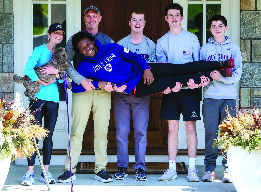 The Miller family standing while holding Taj across their bodies along their hips, Sara Miller is holding the family dog