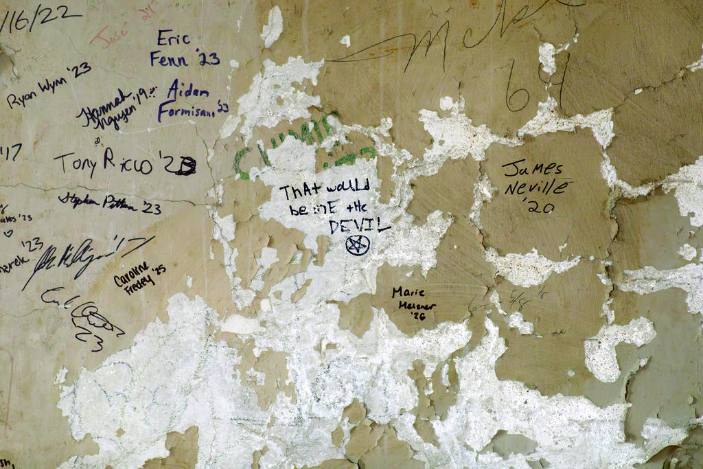 Names scrawled on a wall of peeling paint