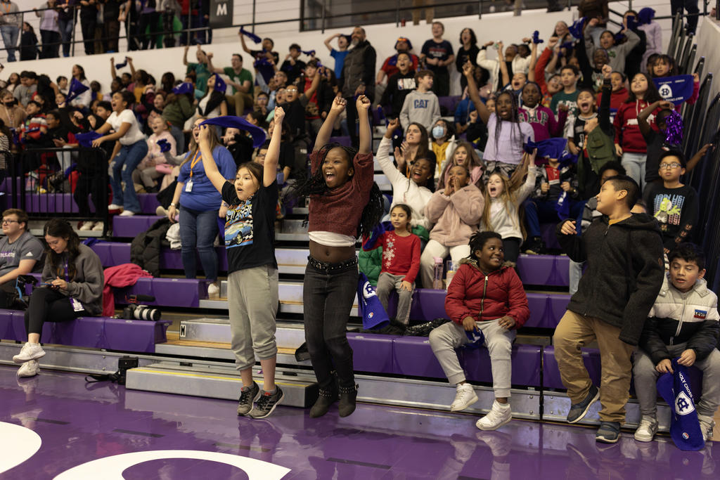 A crowd of young fans cheers at a basketball game