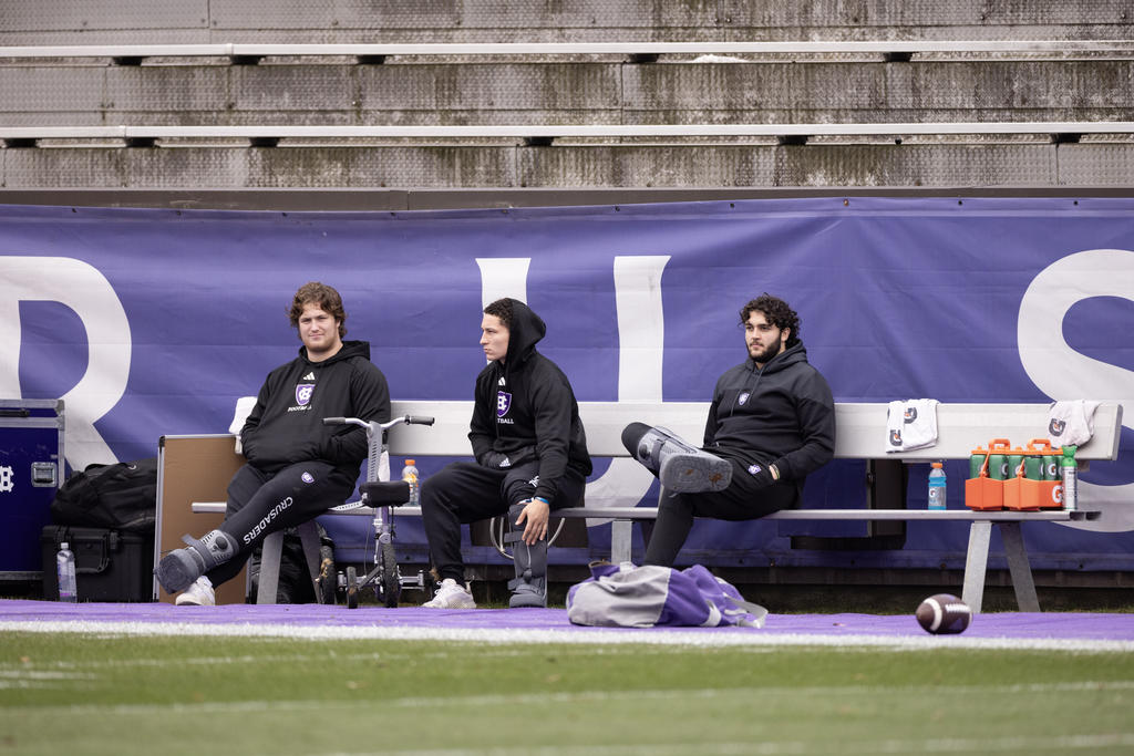 Three men sit on an aluminum bench
