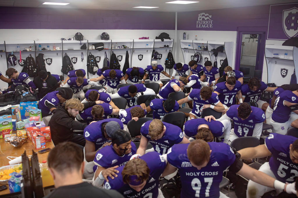 Football team in purple jerseys huddled in locker room