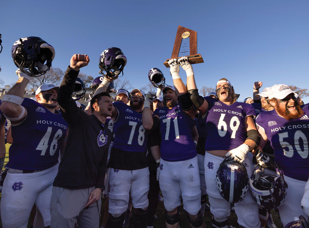 Football players hoist a trophy over their head cheering