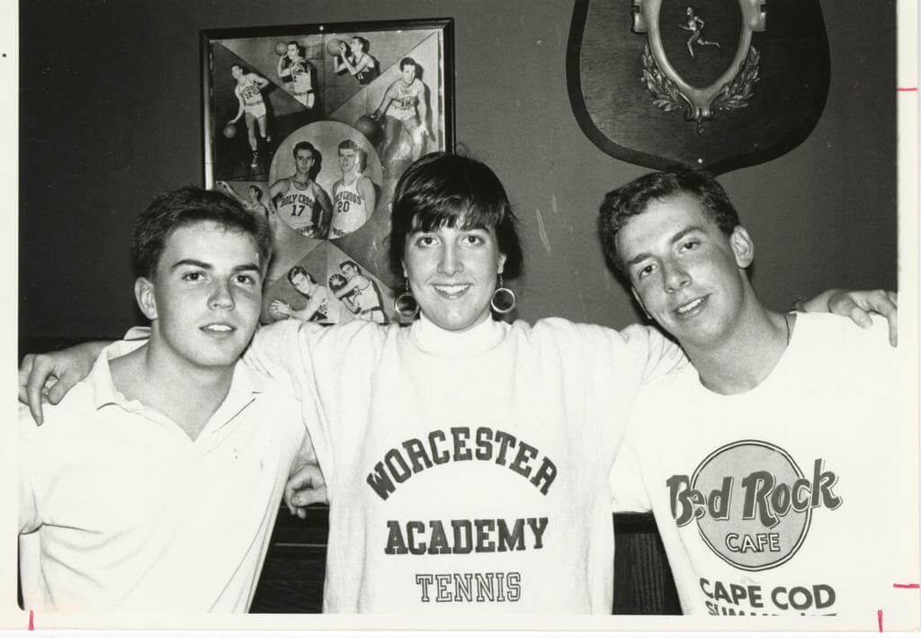 Three students stand arm and arm in a black and white picture.