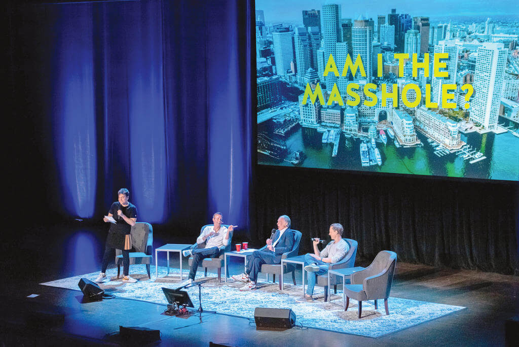 Four men sit on stage during a live Q&A event