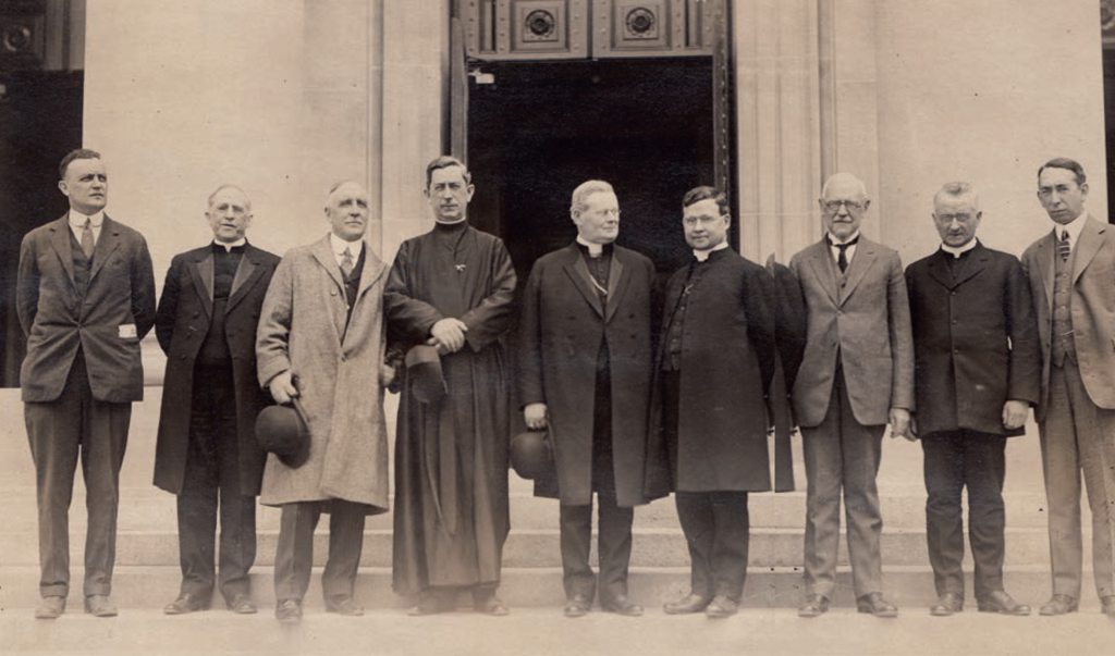 Black and white photo of men standing outside a church entrance