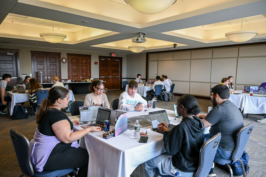 Groups of students sit around tables