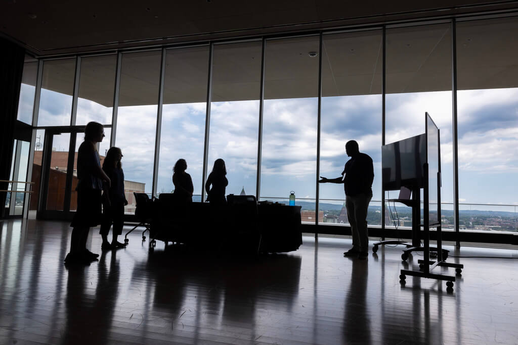 People in shadow surround a monitor