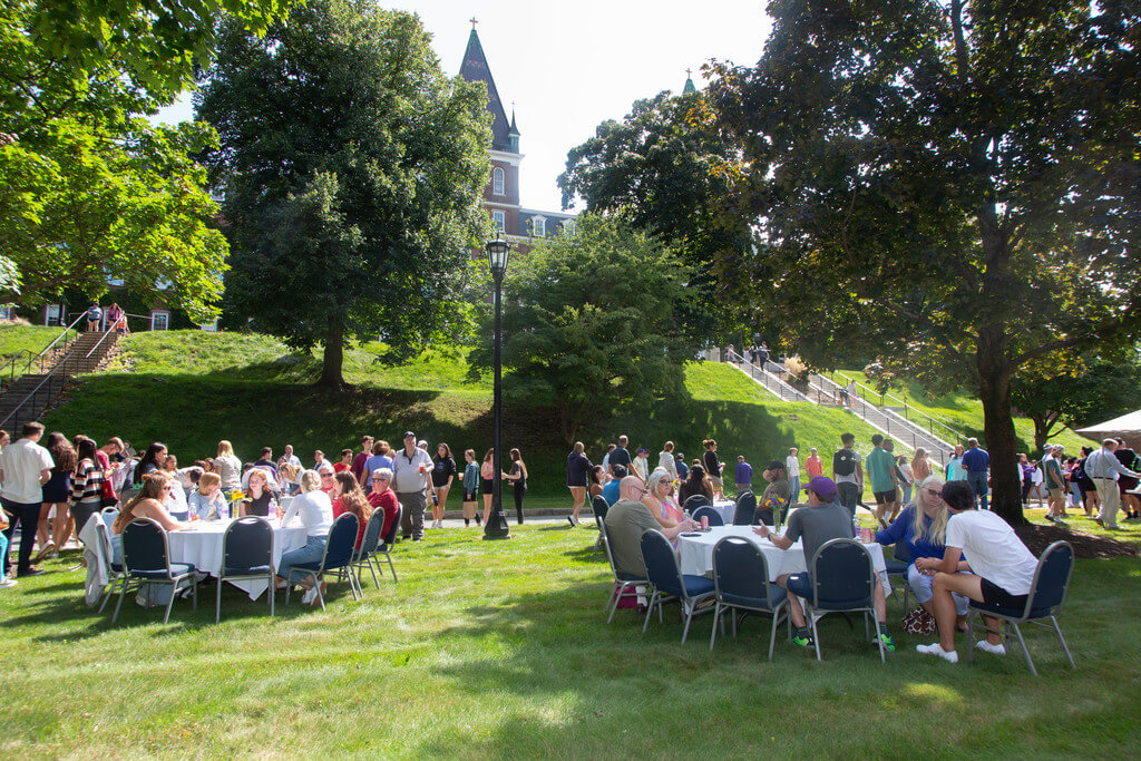 groups of people sit around circular tables outdoors