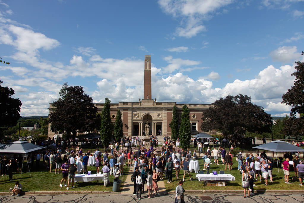 group of people gather on lawn in front of brick building