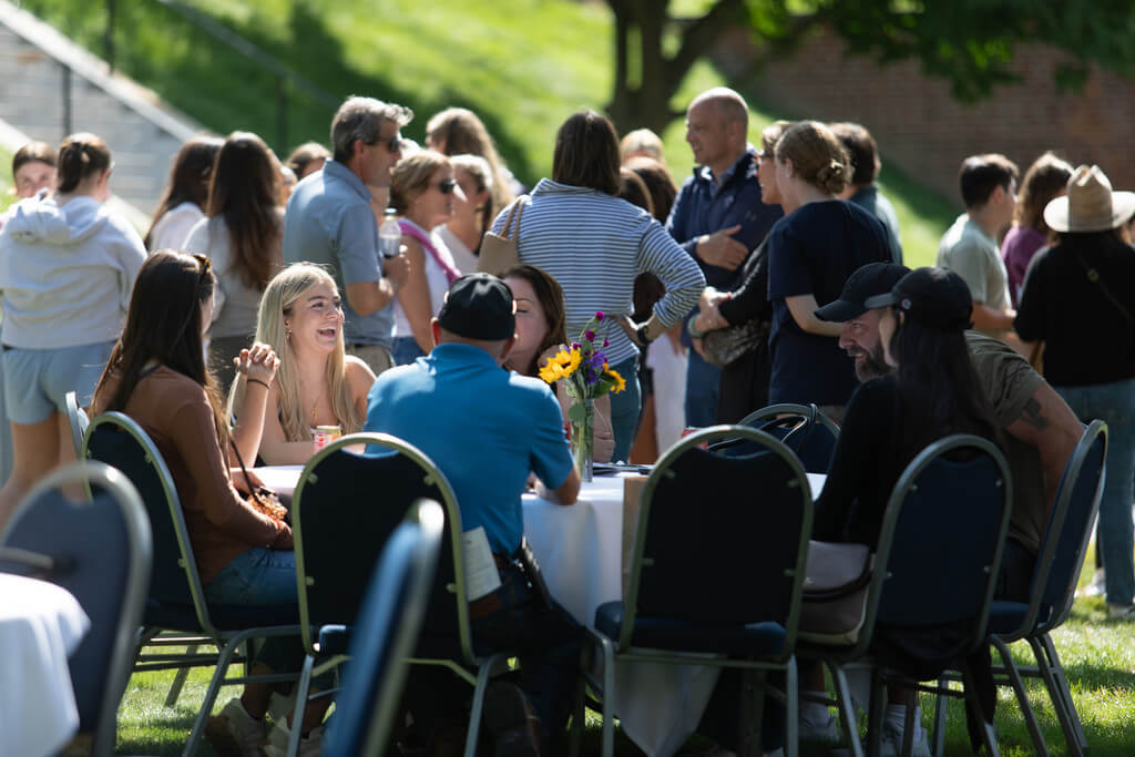 group of people sit at circular table outdoors talking