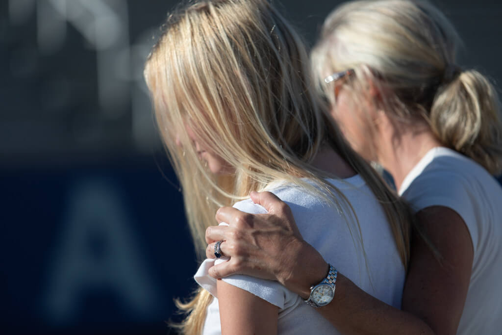 Woman wraps arm around younger woman's shoulder