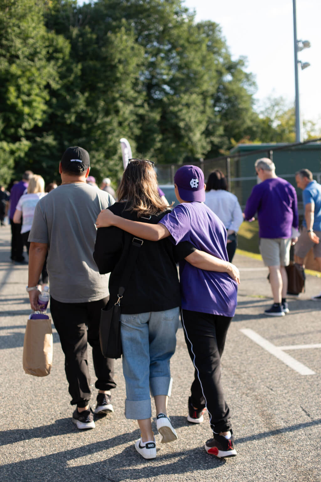 Two women walk away from camera with their arms around each other