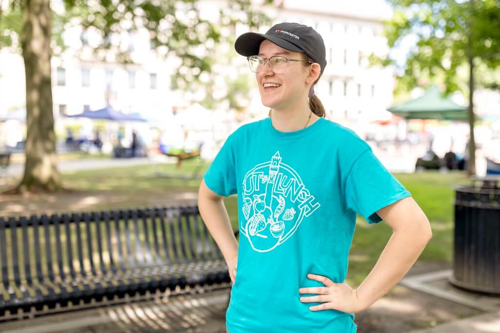 Woman in baseball hat stands with hands on hips