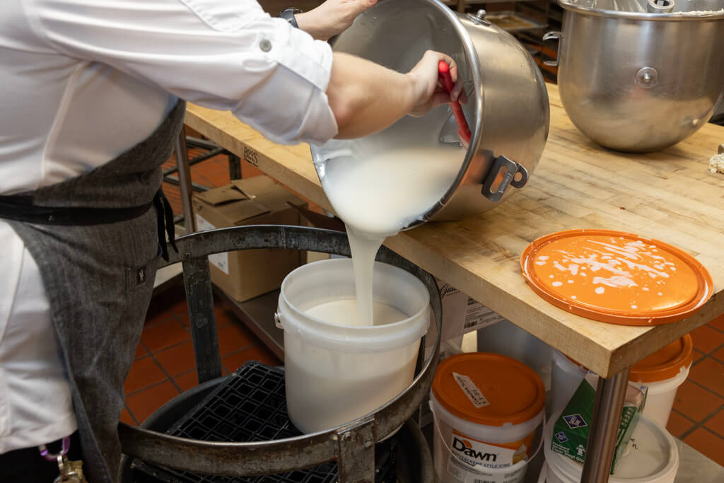 L’Ecoyer mixes the glaze while the donuts cool on wooden dowels. Glaze needs to be applied while the donuts are still warm enough for it to stick, but no so hot that it will slide right off.