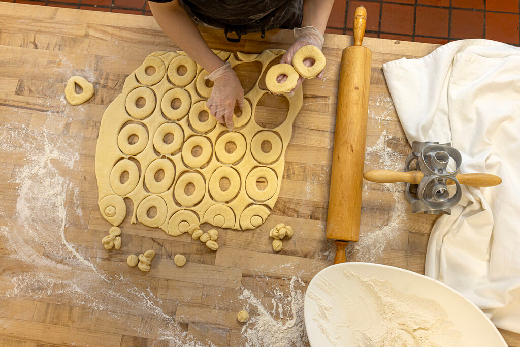 Overhead view of donuts being cut out of a sheet of dough