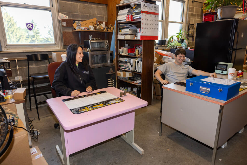 Man and woman sit at desks laughing